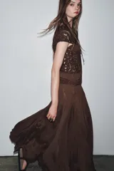 Vestido largo color marrón con detalle de crochet en el corpiño, escote redondo y manga corta. Cierre en la espalda con lazadas.