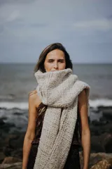 Chal rectangular tejido en punto grueso color beige con detalles dorados.