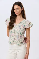 Camisa de lino estampada con diseño floral en tonos lila y verde, mangas cortas con volados y cierre frontal con botones.