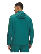 Campera deportiva Under Armour modelo M Challenger Warmup de color verde oscuro, con capucha, cierre de media cremallera y bolsillo frontal con cierre. Presenta detalles de líneas en tono flúor y logo de la marca estampado en blanco en el pecho.