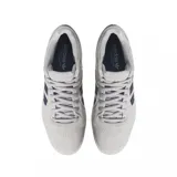 Championes de skate Adidas modelo Tyshawn, color gris claro con las icónicas tres rayas laterales en azul oscuro. Presenta detalles en rojo y azul en el talón, suela blanca y el nombre del modelo grabado en dorado en el lateral.