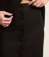 Pollera midi negra de lino con botones forrados en la parte delantera y abertura en el ruedo.
