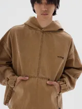 Hoodie de denim color tostado con lavado soft, corte vertical en la parte delantera, bolsillo canguro, puños y dobladillo elásticos. Presenta un bordado de estrella rosa en el pecho izquierdo y el texto "LES ENFANTS 1984" en el pecho derecho.