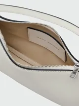 Cartera tipo shoulder bag Marc Jacobs, color blanco, con correa de cadena metálica plateada y detalles colgantes con estrellas.