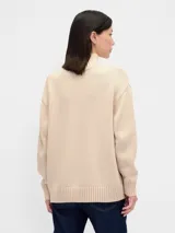 Buzo de algodón color beige con cuello polera, manga larga y diseño holgado con puños y dobladillo en rib.