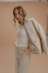 Blazer de lino color beige, de corte estructurado con solapas clásicas, cierre frontal y bolsillos laterales con solapa.