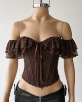 Corset blanco estilo off-shoulder, con escote en V pronunciado, volados de encaje en los hombros y cierre frontal con cordones ajustables.