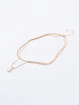 Collar doble de cadena dorada con un dije rectangular que presenta una incrustación de piedra blanca. El diseño incluye una cadena de eslabones planos y una cadena más fina, con cierre de mosquetón y cadena de alargue.