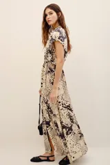 Vestido largo beige con estampado animal print oscuro y detalles en color negro, escote en V y mangas cortas holgadas.
