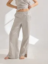 Pantalon de corte recto confeccionado en lino con acabado metalizado. Presenta cintura elastizada y tajos laterales en el ruedo.