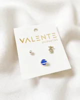 Set de tres pares de aros enchapados en plata. Incluye un par de aros tipo bolita, un par con un dije de un símbolo oriental y un par con un dije de un planeta azul con estrellas.