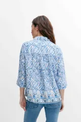 Camisa de mangas 3/4 con estampado abstracto en tonos azules y blancos, con cuello clásico y cierre frontal con botones.