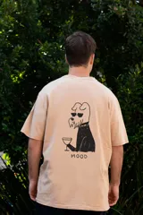 Remera color beige con estampado en la espalda de un perro con gafas de sol y un vaso, con la palabra 'MOOD' debajo.