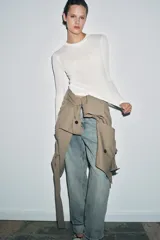 Top de punto fino y semitransparente color gris claro, con cuello redondo y manga larga.