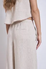 Pantalón de lino color beige, de corte amplio y tiro alto, con cintura elástica y bolsillos laterales.