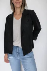 Chaqueta corta de diseño abierto sin cierre, confeccionada en tejido con textura efecto ante. Presenta solapas clásicas y mangas largas, con un corte recto y liviano ideal para media estación.