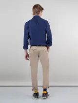 Pantalón chino de hombre color azul marino, de corte slim fit, confeccionado en gabardina de algodón, con bolsillos laterales y traseros, y cierre frontal de cremallera y botón.