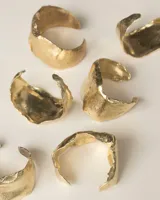 Brazalete rígido plateado con textura irregular.