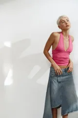 Falda midi de denim con diseño asimétrico en el bajo. Presenta tiro medio, trabillas para cinturón, cinco bolsillos clásicos y cierre frontal con cremallera y botón metálico.