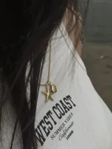Collar dorado con cadena fina y dos dijes: una estrella de mar y una concha marina.