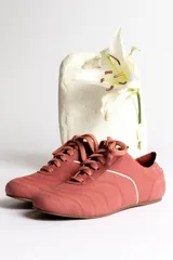 Zapatillas bajas color crema con cordones y suela marrón.