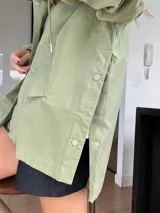 Campera verde claro de corte holgado y mangas largas con puños elásticos. Cierre frontal con botones a presión.