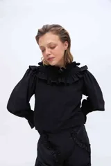 Blusa blanca de algodón con cuello alto fruncido con volados y mangas abullonadas con puños elásticos.