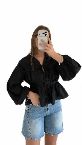 Blusa negra de manga larga amplia, con frunces en el cuerpo y cordones ajustables en el frente y en la cintura.