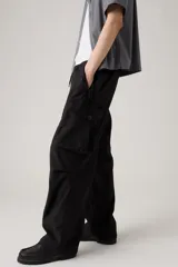 Pantalón cargo negro de corte holgado, con cintura elástica y cordón ajustable. Presenta bolsillos laterales y bolsillos cargo con solapa en los muslos.