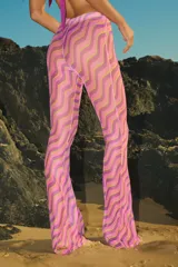 Pantalón de playa confeccionado en tul semitransparente con estampado de ondas en tonos violeta y verde lima. Presenta un corte recto y holgado con cintura elástica.