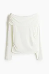 Remera deportiva de manga larga en punto de modal suave, con diseño de hombros descubiertos y escote con solapa doblada. Presenta frunces laterales y aberturas en los puños.