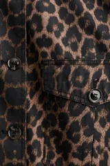 Campera de sarga de algodón con estampado animal print, cuello abierto, cierre frontal con botones y bolsillos delanteros de parche con solapa. Presenta hombros levemente caídos y puños abotonados.