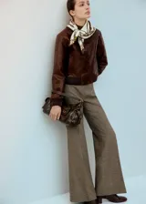Chaqueta estilo bomber color marrón con textura efecto cocodrilo, cierre frontal con botones, cuello clásico y puños y cintura de canalé elástico.