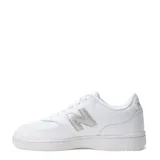 Championes urbanos New Balance, modelo Court, color blanco con logo lateral en plateado texturizado. Presentan puntera perforada para mayor ventilación y suela de goma al tono.