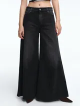 Pantalón de jean negro con corte wide leg, tiro medio y diseño de cinco bolsillos. Presenta un lavado desgastado y cierre frontal con botón y cremallera.