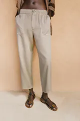 Pantalón de tiro medio color amarillo, con cintura elástica, bolsillos de plastrón en el delantero y pernera holgada que se estrecha hacia el tobillo. Cuenta con cierre frontal de cremallera y botón.