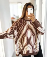 Sweater de punto con diseño abstracto en tonos chocolate, marrón claro y crudo. Presenta cuello redondo, mangas largas con puños acanalados y un corte holgado oversize.