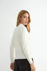 Polera de punto color beige, con cuello alto y mangas largas, de diseño básico y ajuste clásico.