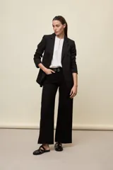 Blazer negro de líneas clásicas y silueta sastrera, con solapas y estructura definida.