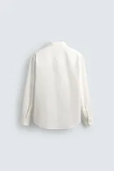 Camisa de corte relajado confeccionada en una mezcla de algodón, lyocell y seda de origen italiano. Presenta cuello abotonado, manga larga con puños abotonados y cierre frontal con botones.
