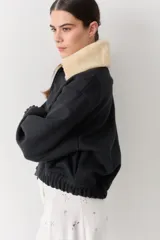 Campera bomber de paño color beige, con cierre frontal, cuello alto y puños elásticos.