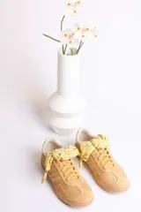 Zapatillas bajas color marrón con cordones y charms dorados.