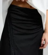 Pollera midi de tul color negro con caída fluida, transparencia sutil y abertura frontal con detalle de encaje. Presenta cintura ajustada y forro interior.