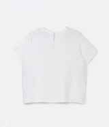 Blusa de manga corta color beige, confeccionada en tela texturizada. Presenta cuello redondo con detalle de pespuntes y cierre trasero con botón en forma de lágrima.