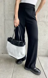 Pantalón negro de lino, de corte ancho y largo, con diseño suelto y botones decorativos en la cintura.