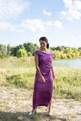 Vestido midi color violeta metalizado, con escote bote drapeado, sin mangas y diseño fluido con pliegues laterales.