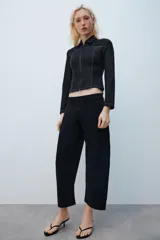 Camisa de denim negra con cuello solapa, manga larga, pespuntes a contraste y cierre frontal con cremallera metálica.