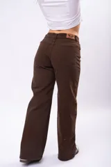 Pantalón de corte wide leg en color marrón, confeccionado en tejido con elastano. Presenta tiro medio, cierre frontal con botón y bolsillos laterales.