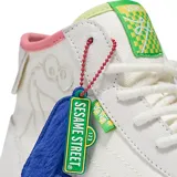 Zapatillas de caña alta Vans x Sesame Street, color blanco con detalles en rosa, verde y celeste. Presentan un dibujo de Elmo en el lateral y un dije de felpa con la letra L.