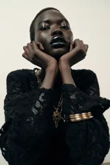 Top de encaje negro con cuello redondo, manga larga y hombreras incorporadas. Presenta un diseño de corte recto y cierre posterior.